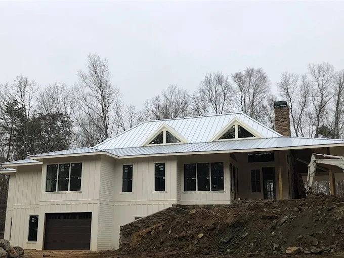 Completed white standing seam metal roof on a modern farmhouse