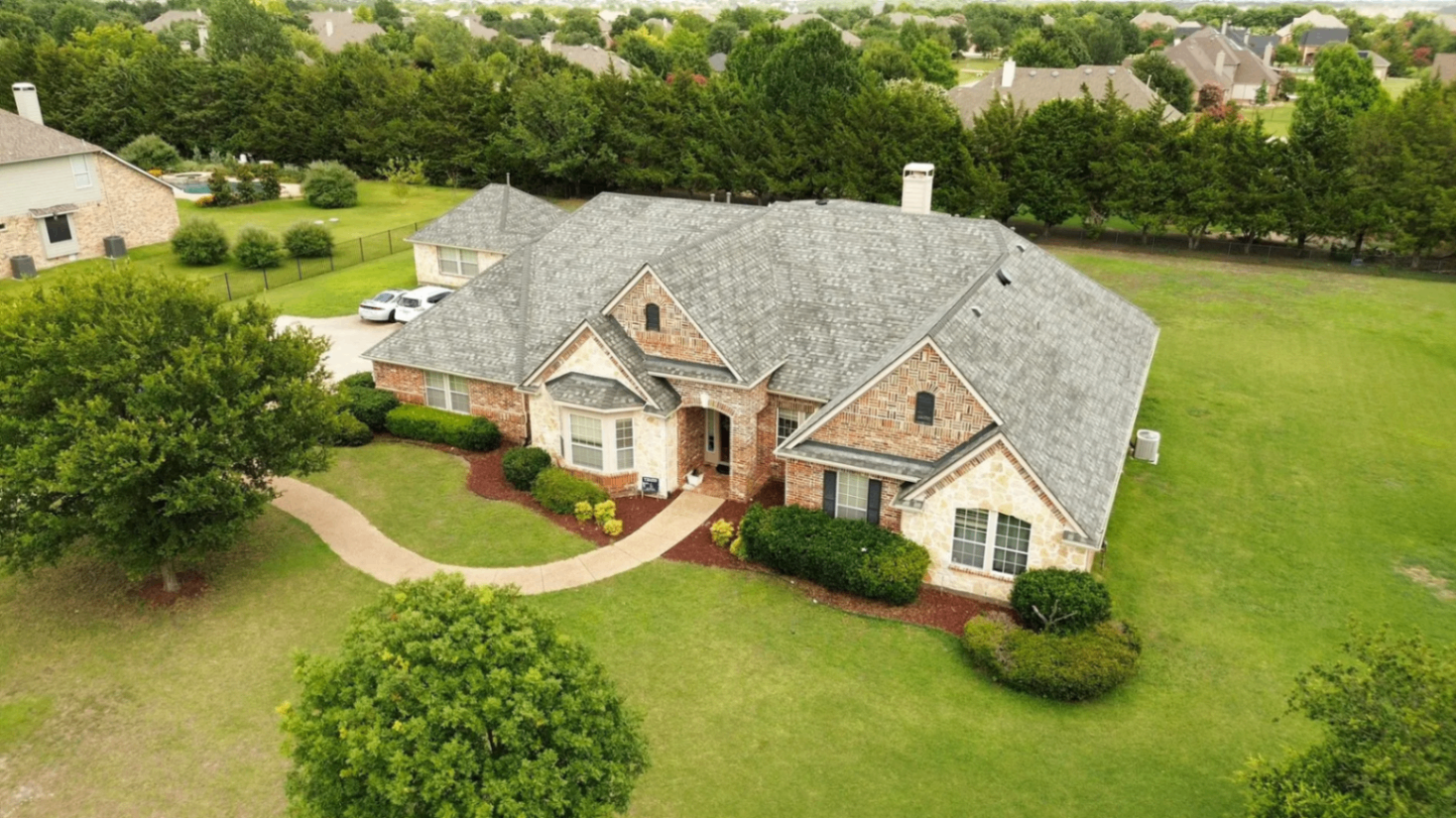 Completed shingle roof on a brick and stone ranch home with a large lawn