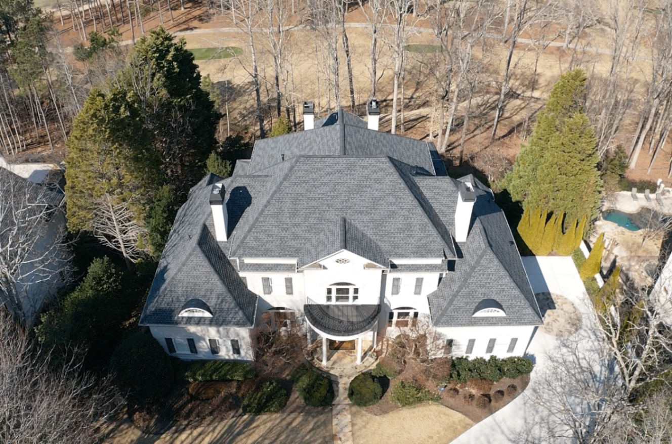 Aerial view of a completed slate-grey shingle roof on a large white Charlotte estate
