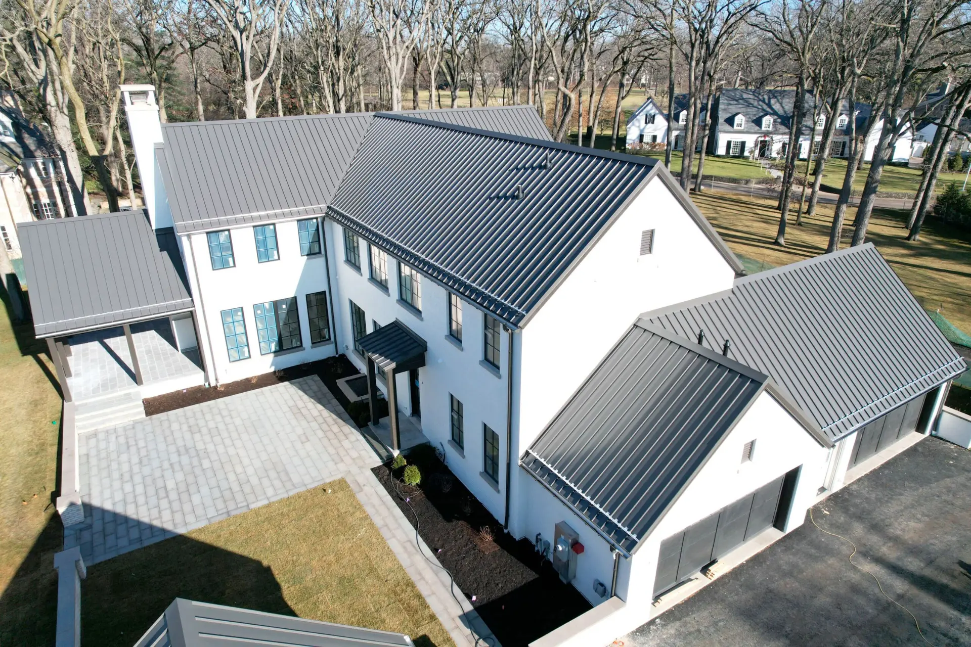 Aerial view of a dark standing seam metal roof on a large white modern estate