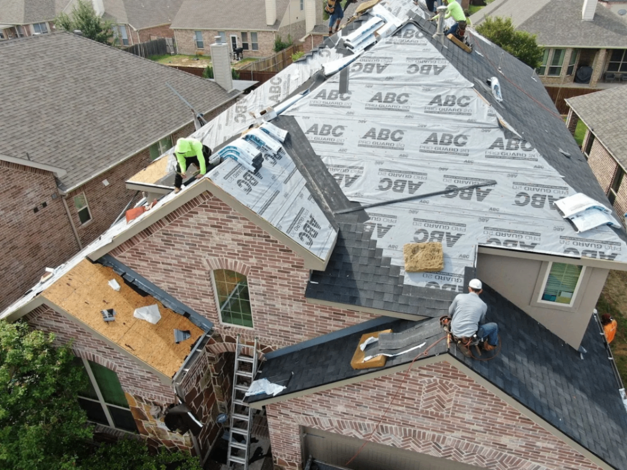 Copper Crow crew installing underlayment and shingles on a brick two-story home