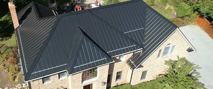 Aerial view of a black standing seam metal roof on a brick home