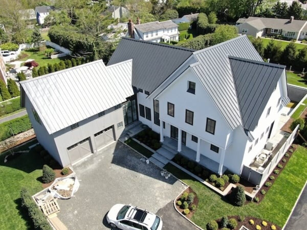 Aerial view of a two-tone standing seam metal roof on a white modern farmhouse